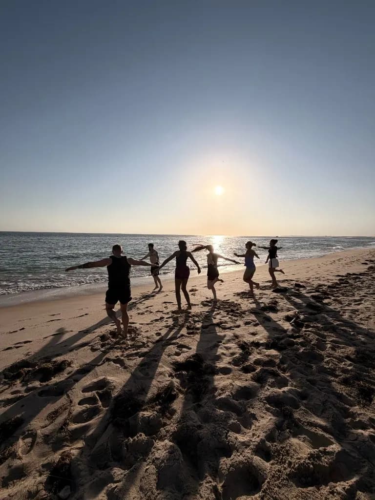 Group running on the beach at sunset in Faro