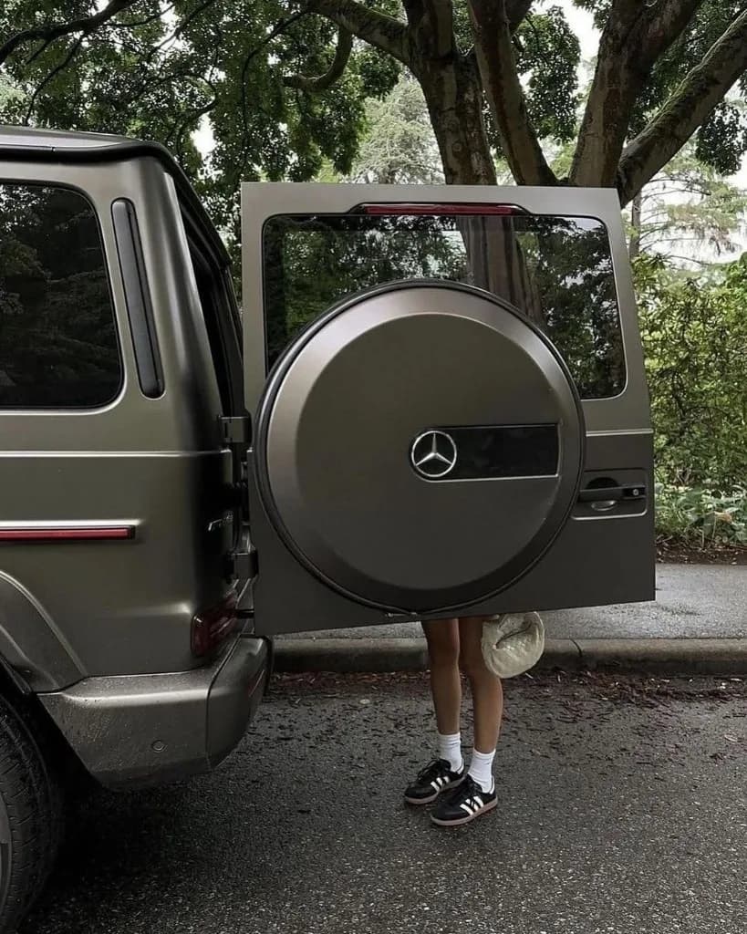 Geöffnete Hecktür einer G-Class auf einer baumgesäumten Allee — Detailaufnahme