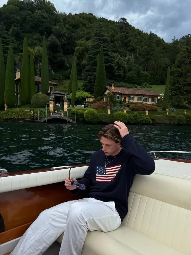 Junger Mann auf einem klassischen Holzboot vor einer Villa am Comer See