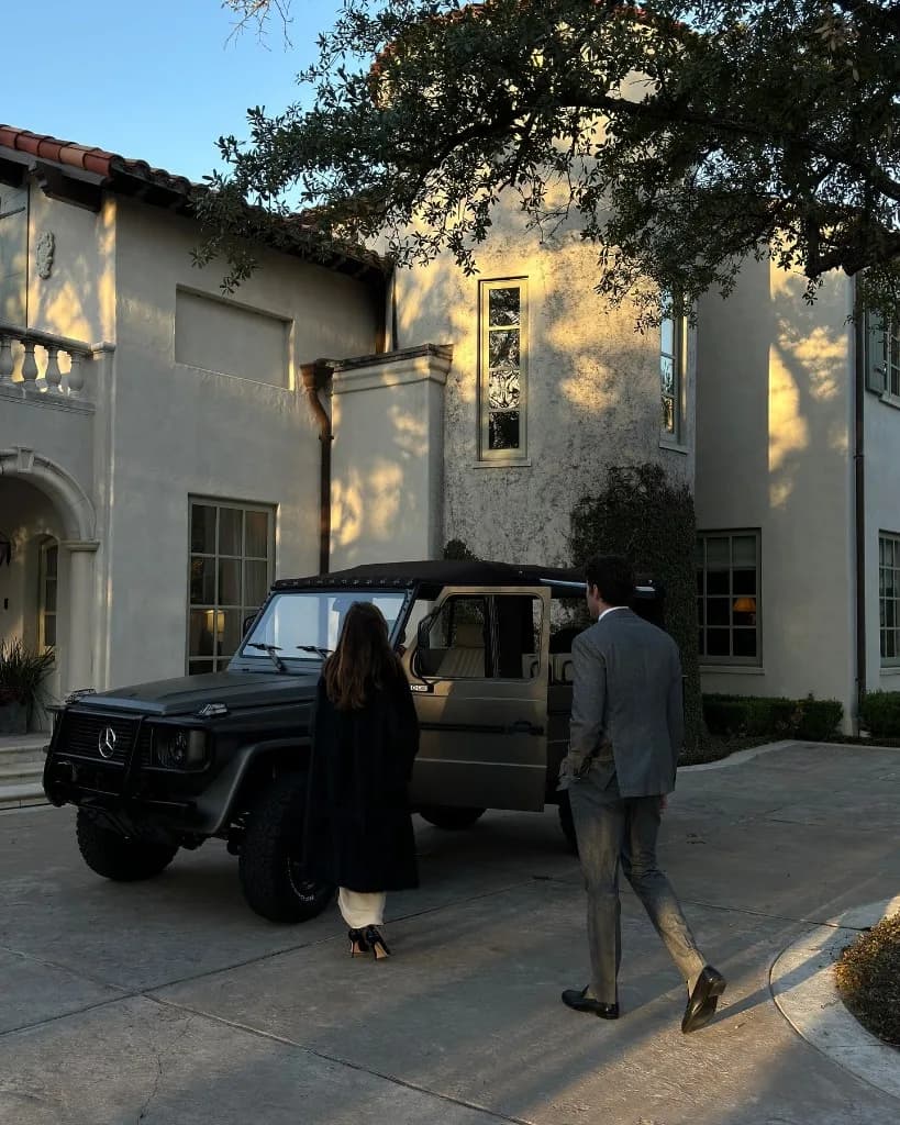 Paar im Abendlicht neben einer G-Class vor einer Villa