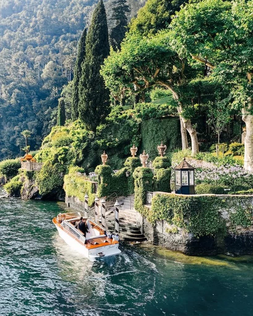 Klassisches Holzboot vor einer Villa am Comer See im Abendlicht