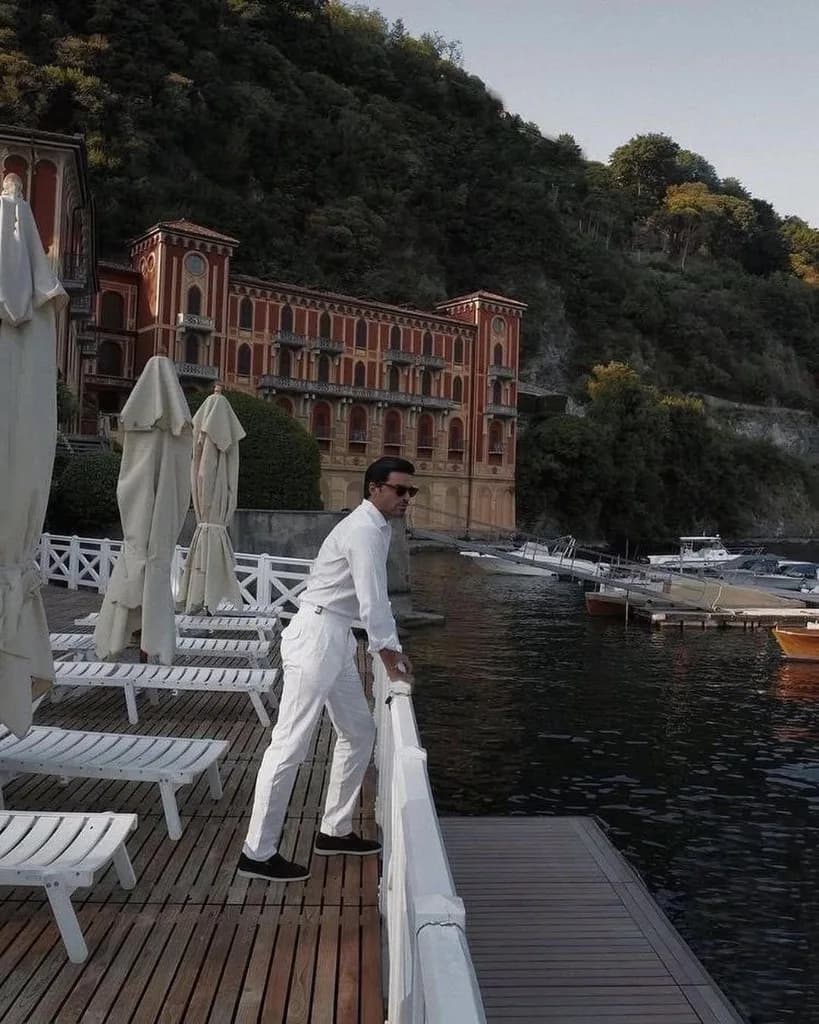 Mann in Weiß auf einem Holzsteg am Comer See, Villa im Hintergrund, frühe Abendstimmung