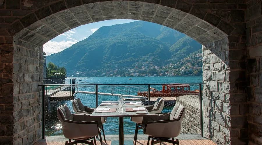 Gedeckter Tisch unter einem Steinbogen mit Blick auf den Comer See und die Berge