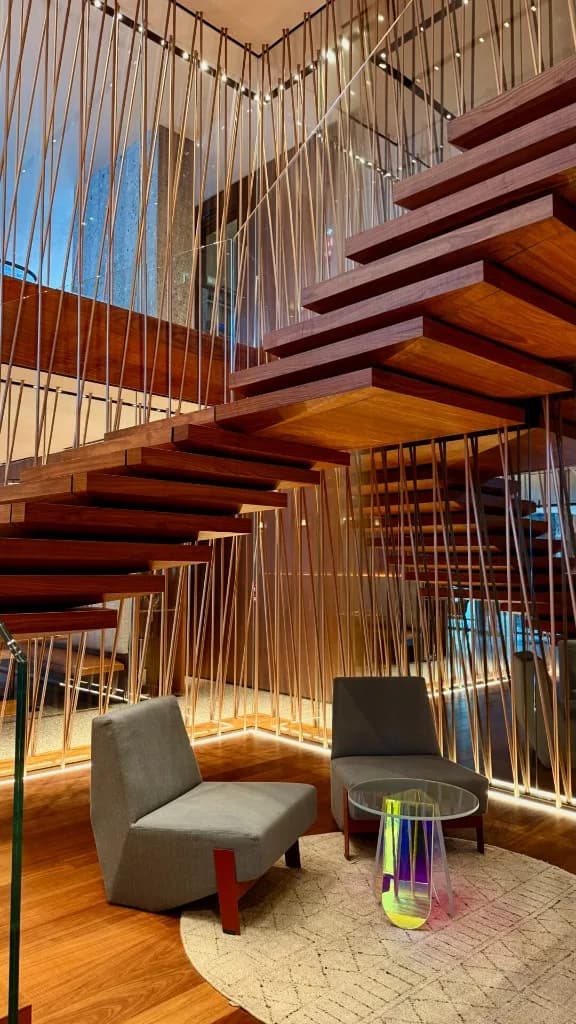 Skulpturale Holztreppe in einer ruhigen Lobby — warmes Licht am Abend