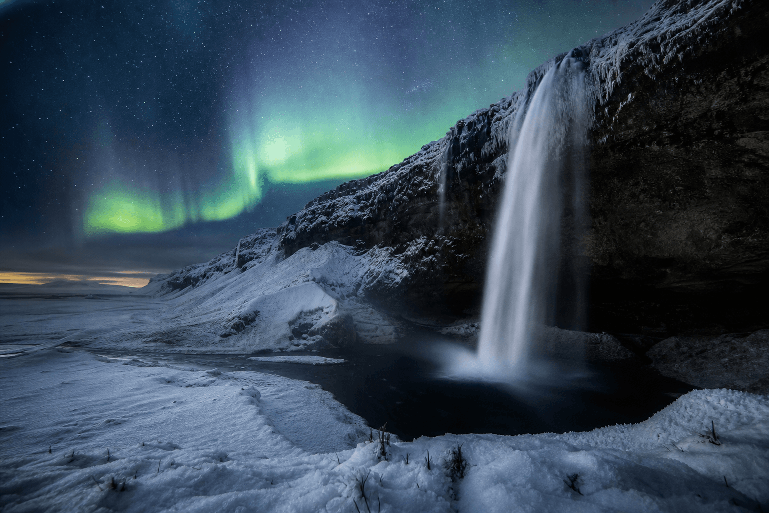 Island — Seljalandsfoss mit Schnee und Nordlichtern